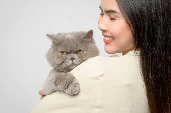 A young woman is holding lovely cat , playing with cat in studio on white background