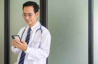 Hastanede beyaz önlüklü, kendinden emin gülümseyen bir doktorun portresi.