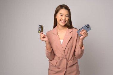 A Young asian woman holding credit card over white background studio, shopping and finance concept.
