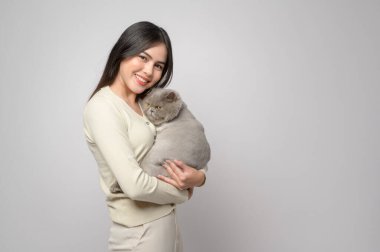 A young woman is holding lovely cat , playing with cat in studio on white background 