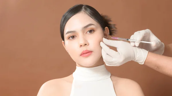 Portrait Beautiful Young Woman face and doctor hands wearing  gloves holding Syringe, Facial Beauty Injections concept