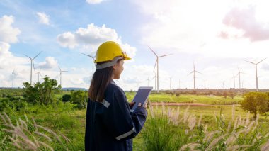 a woman engineer is wearing a protective helmet on her head, using tablet Analytics engineering data.	