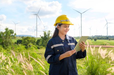 a woman engineer is wearing a protective helmet on her head, using tablet Analytics engineering data.	