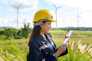 a woman engineer is wearing a protective helmet on her head, using tablet Analytics engineering data.	