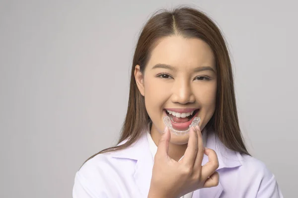 一名年轻的女牙医在白人背景演播室 牙科保健和牙齿矫正概念的基础上 手持无创矫形器架 — 图库照片