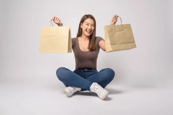一个年轻的亚洲女人拿着购物袋在白色的背景工作室 购物和金融的概念 — 图库照片