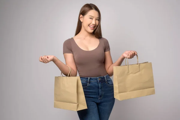 一个年轻的亚洲女人拿着购物袋在白色的背景工作室 购物和金融的概念 — 图库照片