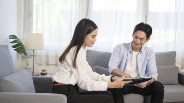 Genç bir erkek, kadın emlakçıyla ya da sigorta danışmanıyla görüşerek terfi, ipotek, kredi, mülk ve sağlık sigortası konsepti sunar.. 