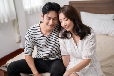 Evdeki yatak odasında gülümseyen Asyalı genç bir çiftin portresi, aile kavramı..