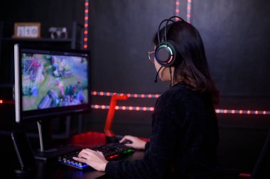 Çevrimiçi video oyunları oynayan kulaklıklı genç bir bayan profesyonel Streamer ve oyuncu.