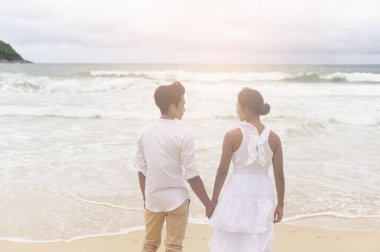 A Happy young couple wearing white dress on the beach on holidays, travel, romantic, wedding concept