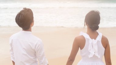 A Happy young couple wearing white dress on the beach on holidays, travel, romantic, wedding concept