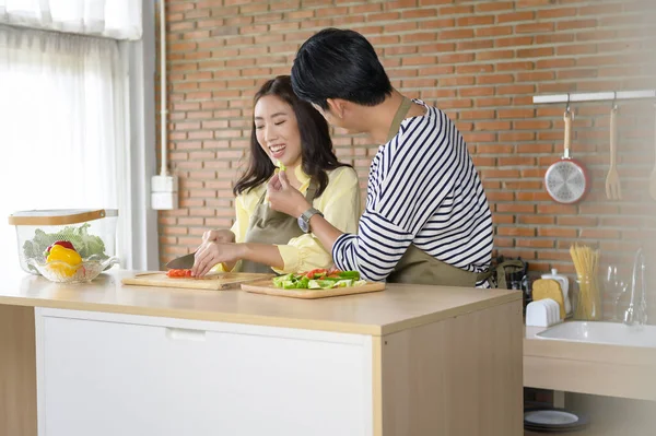 A Young smiling asian couple wearing an apron in the kitchen room, cooking concept