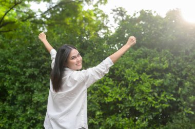 Genç, sağlıklı bir kadın gülümsüyor, doğada ferahlatıcı. 