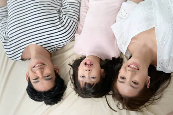 亚洲父母的头像 他们的小女儿躺在床上 享受着幸福的家庭观念 — 图库照片