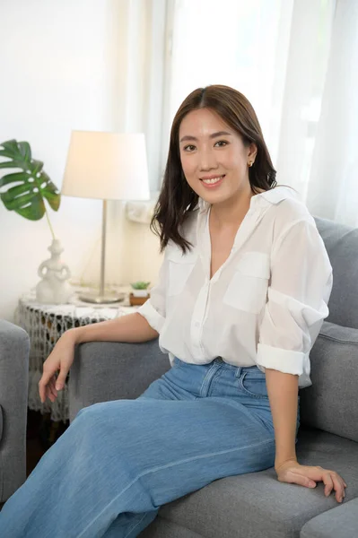 リビングルームでソファで笑顔若いアジアの女性の肖像画 — ストック写真