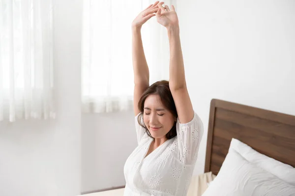 ベッドルームのベッドで目を覚ます若いアジア人女性幸せな健康的なライフスタイルのコンセプト — ストック写真
