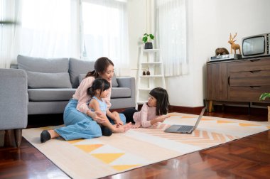 Çocuklu Asyalı bir aile evde dizüstü bilgisayar kullanıyor. 