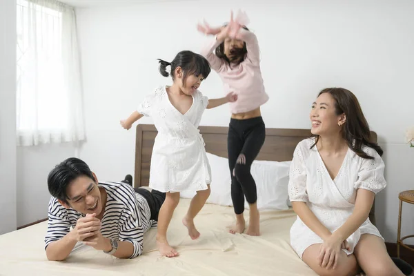 二人の娘を持つアジアの両親ベッドルームでベッドの上でジャンプ 幸せな家族の概念 — ストック写真