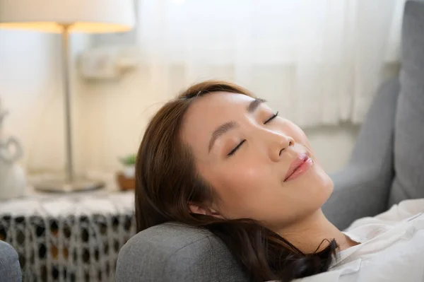 Young asian woman napping on the sofa in living room , happy healthy lifestyle concept