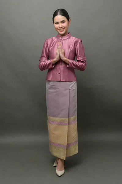 灰色の背景にタイの伝統的な布を身に着けている若いアジアの女性 — ストック写真