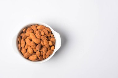 Beyaz arka planda kavrulmuş badem, sağlıklı yiyecek kavramı. 