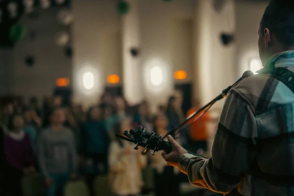 Gitarist büyük bir salonda konser veriyor.
