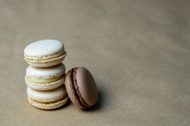 Kahverengi rengin yanında üç açık bej badem kurabiyesi var.