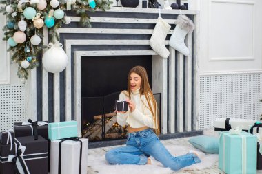 Noel hediyelerini süslenmiş bir Noel ağacının yanında açan genç bir kadın. Noel, Yeni Yıl Kutlama Konsepti.