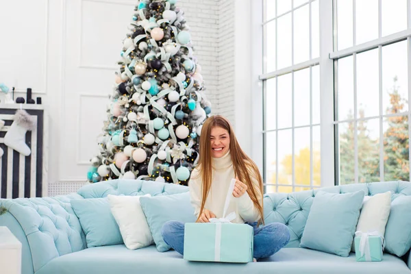 Junge Frau Beim Auspacken Von Weihnachtsgeschenken Neben Einem Geschmückten Weihnachtsbaum — Stockfoto