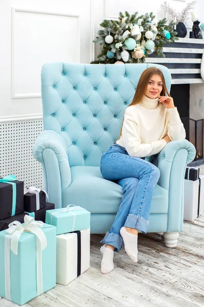 Noel, mutluluk konsepti. Bir sürü hediye kutusuyla gülümseyen kadın. Noel ağacının arka planındaki kız. Mutlu genç bayan Noel 'i kutluyor.