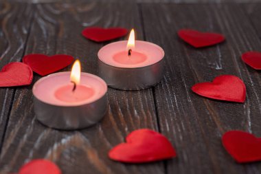 Romantic concept with candle and hearts on a wooden background. St. Valentine's Day