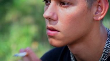 Genç bir delikanlı yazın parkta sigara içiyor, yanlış bir hayat sürüyor.