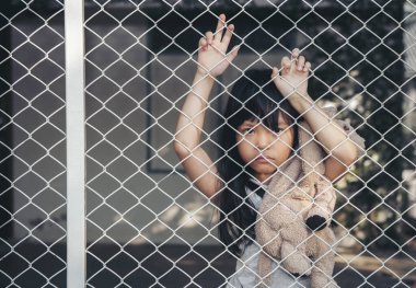 Asyalı çocuk alıngan ya da öfkeli kız üzgün ağlıyor ya da problemleri var ve yalnız başına başını eğiyor. Kafese karşı yalnız bir çocuk. Evde ağlayan küçük bir kız. Şiddet kavramı 