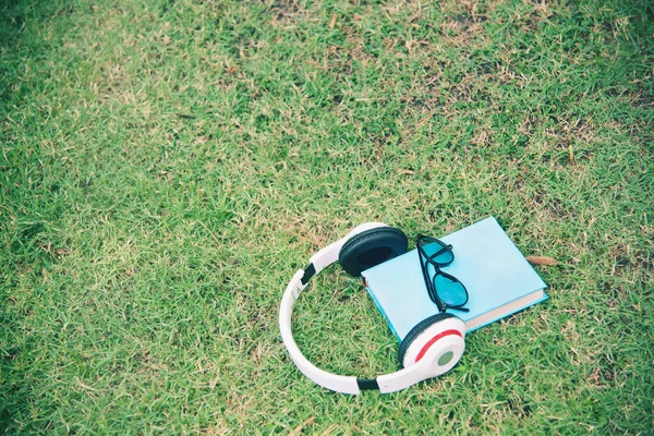 Beyaz Kulaklık Mavi Kitap Siyah Gözlükler Yeşil Çimenlere Takılan Alet — Stok fotoğraf
