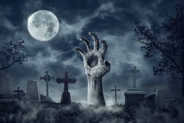 Zombie Hand Rising Out Of A Graveyard cemetery In Spooky dark Night full moon. Holiday event halloween concept.