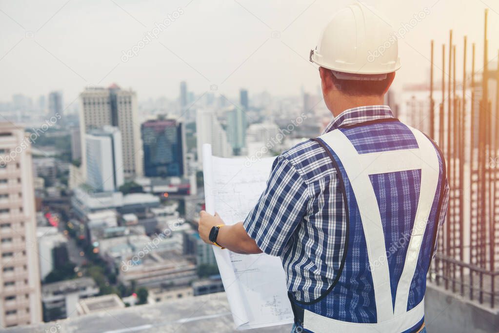 The worker builder foreman engineering occupation working with construction site project background. person looking plan paper to made floor business tower building. industry achitecture building concept. 