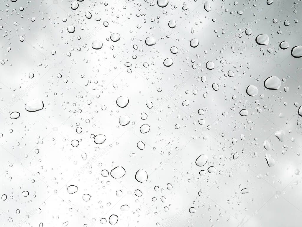 Drops of water from rainning on glass. Selective focus. white gray clouds background pattern texture.