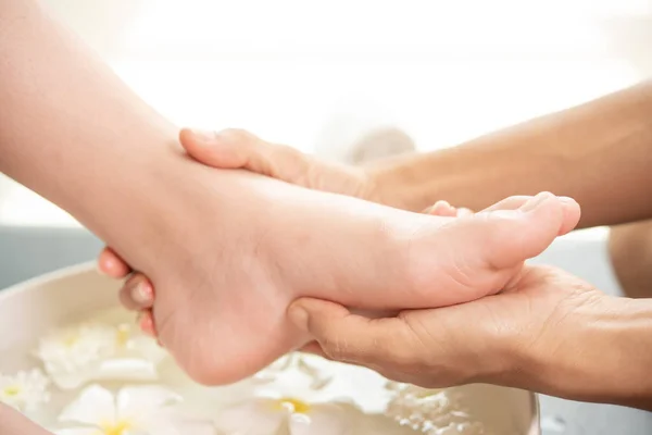 foot washing in spa before treatment. spa treatment and product for female feet and hand spa. white flowers in ceramic bowl with water for aromatherapy at spa.