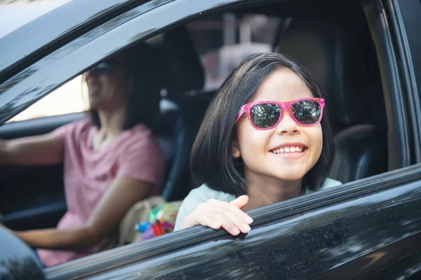 Family vacation holiday, happy family on a road trip in their car, mom driving car while her daughter sitting beside, mom and daughter are traveling. summer ride by automobile.