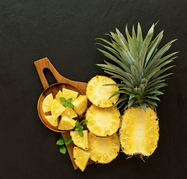 Whole and sliced pineapple on the black texture background. .have a lot of fiber,vitamins C and minerals. food, fruits or healthcare concept.