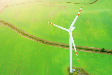 Elektrik üreten rüzgar türbini, yeşil bir alanın arka planında yel değirmenleri, alternatif bir enerji kaynağı, insansız hava aracının görüntüsü.