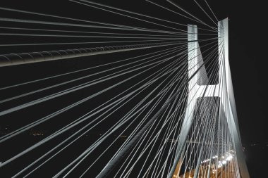 Alacakaranlıkta Wroclaw 'daki Redzin Köprüsü beyaz lambalar ve kutup direkleriyle güzelce aydınlatılmış.