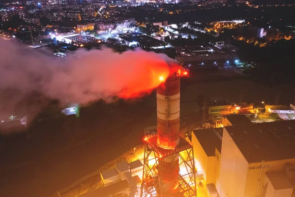 Chimney and a lot of white smoke at the factory, at night, from a height