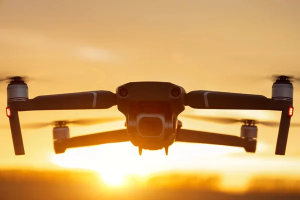 Gün batımında dijital kamerayla uçan insansız bir kuadkopter. Gün batımında drone silueti