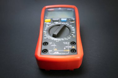 Kırmızı çoklu metre, çoklu metre ya da çoklu test cihazı, koyu arkaplanda modern çoklu voltaj ölçme aracı