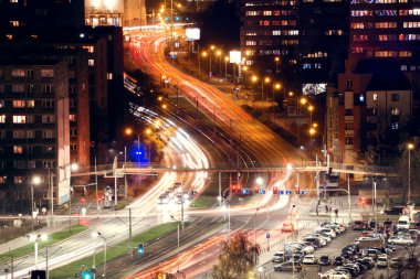 Neon ışıklı hareket etkisine sahip dolambaçlı şehir yolunun soyut hareketi. Polonya 'nın Wroclaw şehrinin şehir caddesinin tepesinden görüntü
