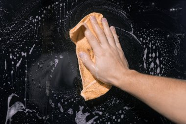 Temizlik. Adamın eli bir bez parçası tutuyor ve camları köpükle yıkıyor..