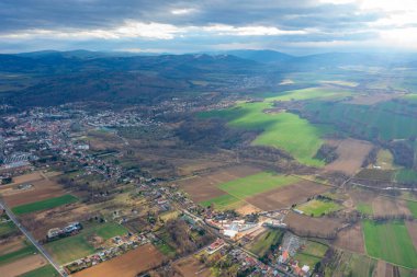 A small Polish town at the foot of a mountain. Small houses, and a church. Landscape from a bird's eye view on the fields of igor
