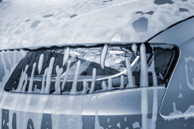 Car headlight in foam, outdoor car wash